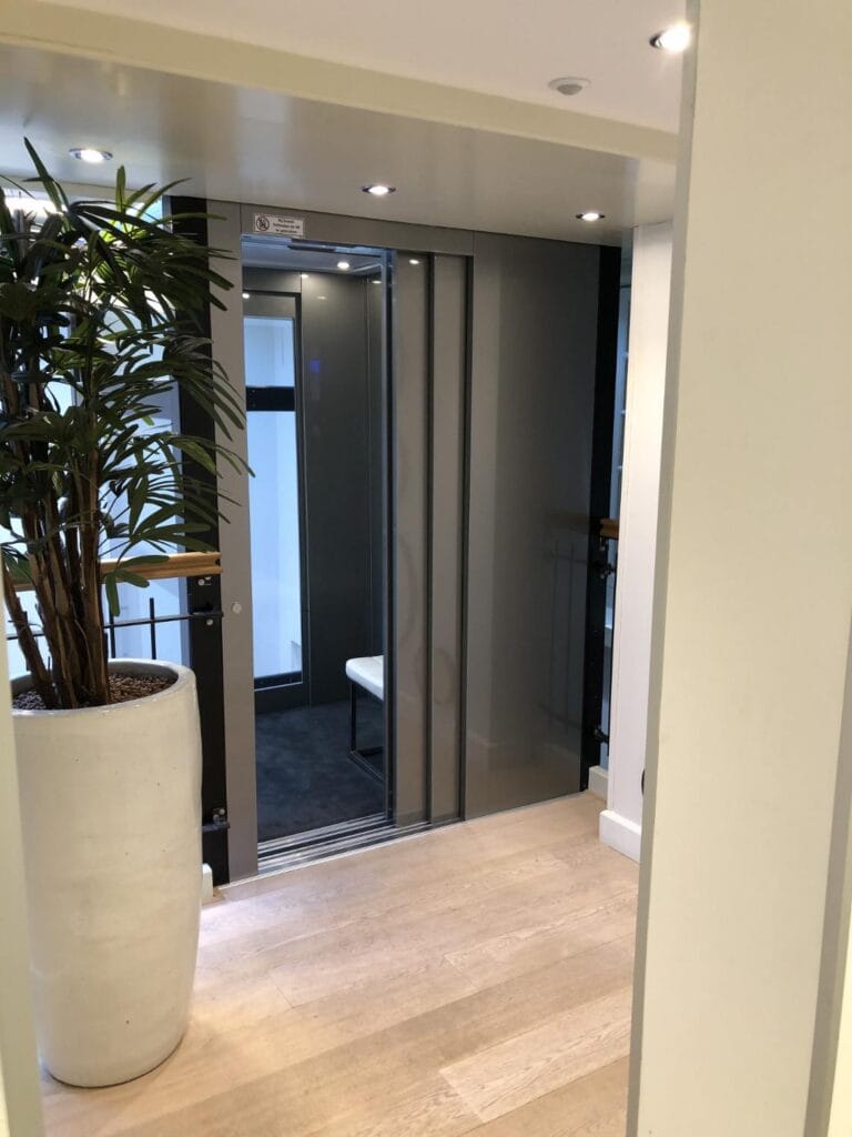 Stijlvolle cabinelift met grijze schuifdeuren in de moderne hal van een uitzendbureau in Rotterdam