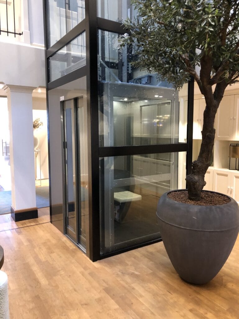 Glazen cabinelift met zwart stalen frame geïnstalleerd in modern kantoorpand in Rotterdam