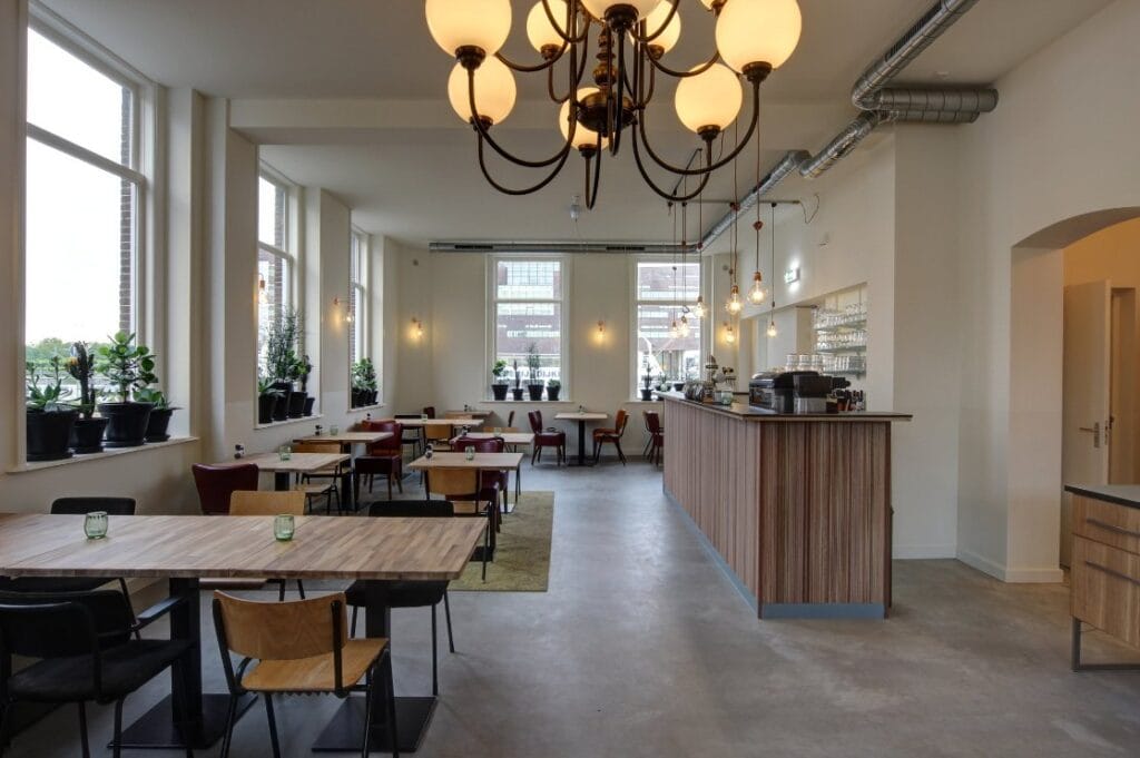 Lichte restaurantzaal van Hotel Loskade 45 met houten tafels en een stijlvolle bar