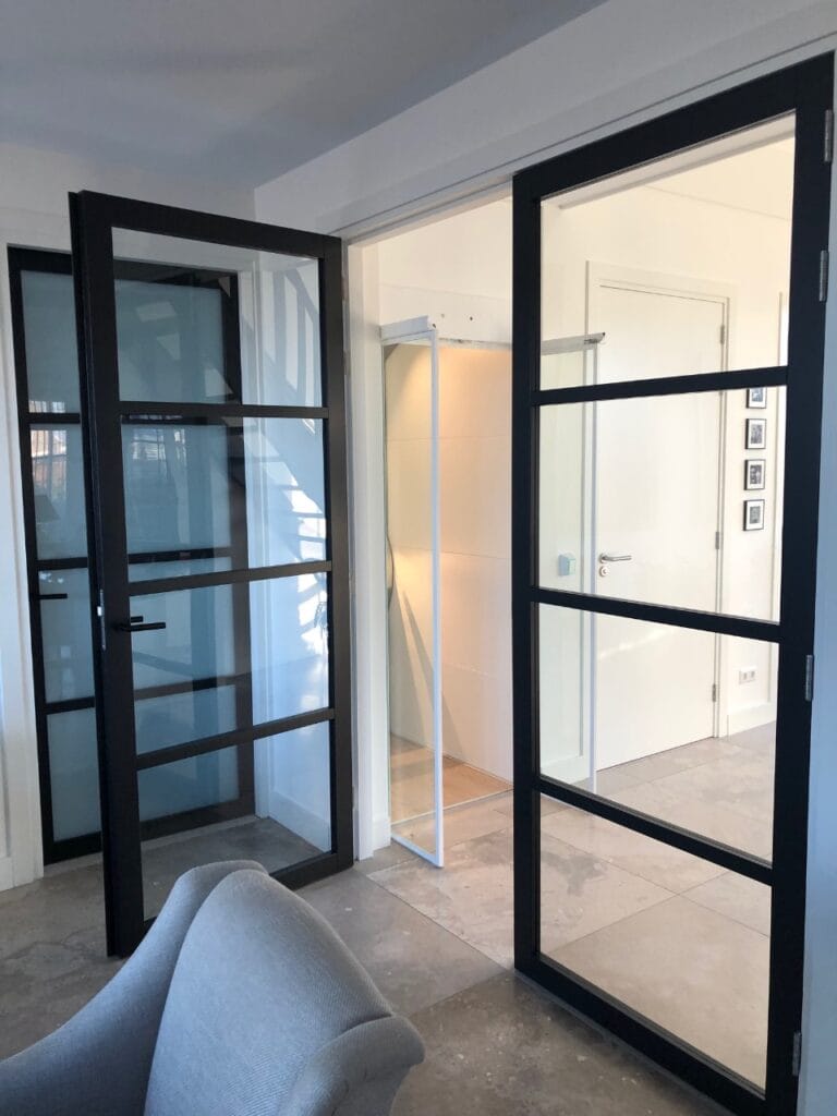 Woonhuislift zichtbaar tussen stijlvolle stalen deuren met glas in modern interieur Noordwijkerhout