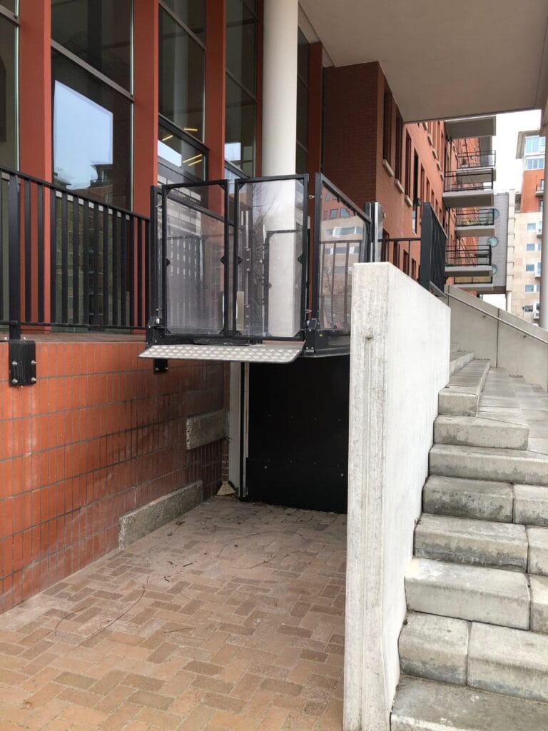 Buitengeplaatste platformlift naast betonnen trap bij appartementencomplex Maanplein Den Haag