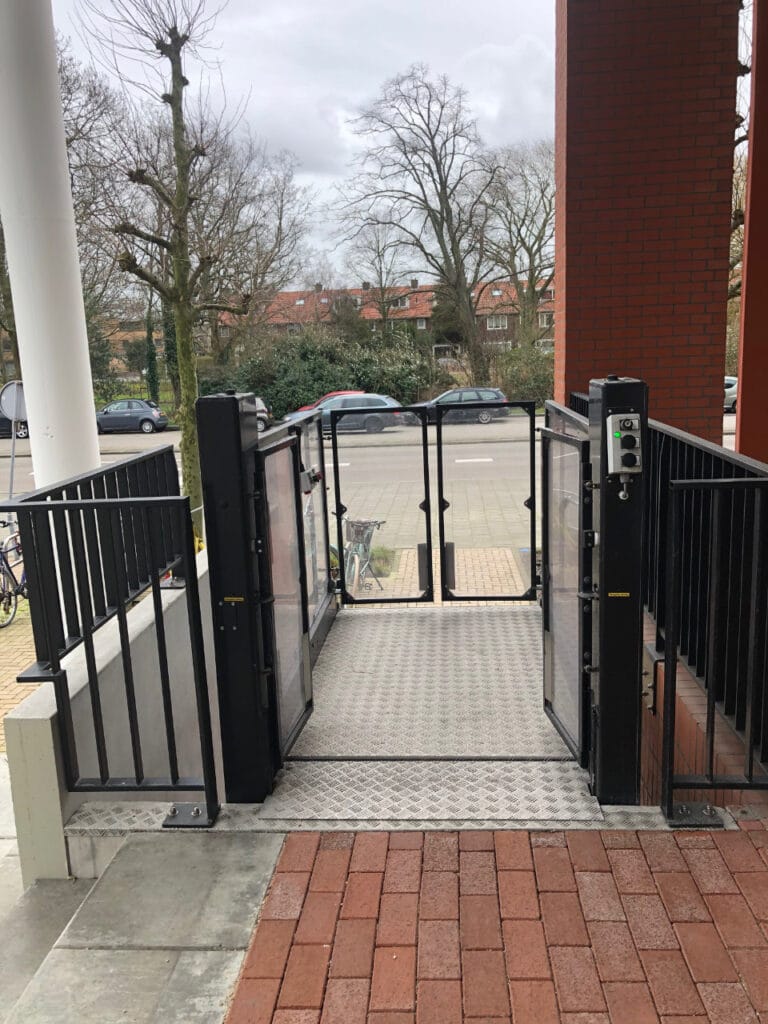 Buitenopgestelde platformlift met open deuren bij appartementencomplex Maanplein in Den Haag