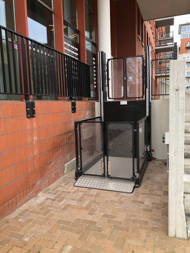 Zwarte platformlift geïnstalleerd aan de buitengevel van een gebouw op het Maanplein in Den Haag