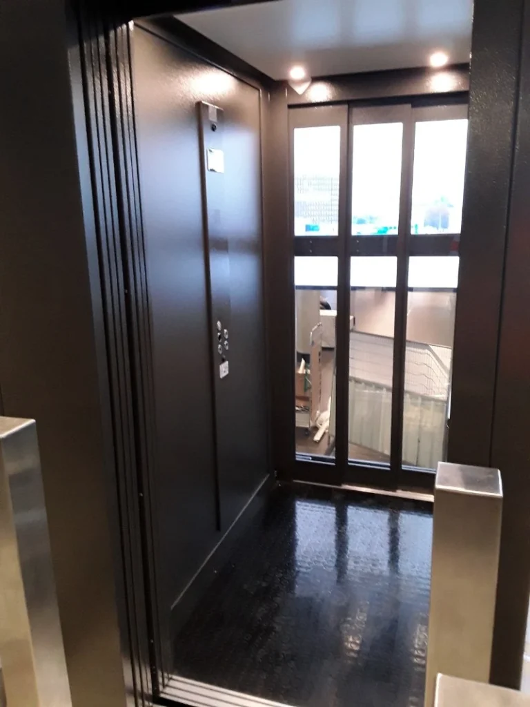 Interieur van een donkere cabinelift met glazen wand geplaatst bij NS Amsterdam