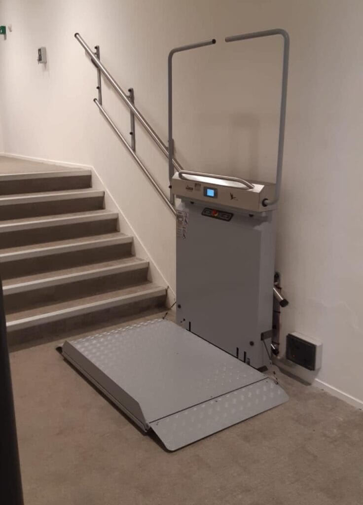 Plateautraplift met neergeklapt platform onderaan een rechte trap in Hotelschool Den Haag