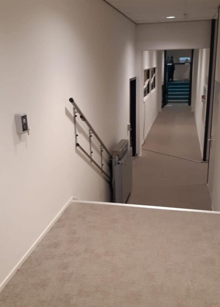 Ingeklapte plateautraplift langs de muur van een gang in Hotelschool Den Haag