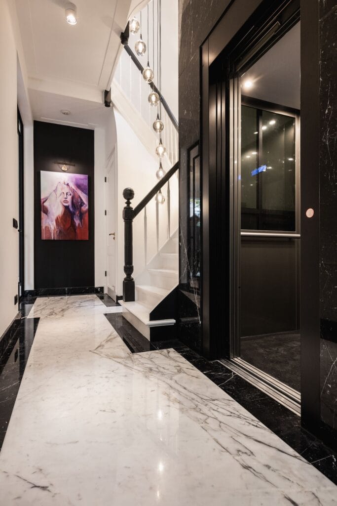 Stijlvolle woonhuislift met zwart marmeren omlijsting in een luxe hal in Den Haag