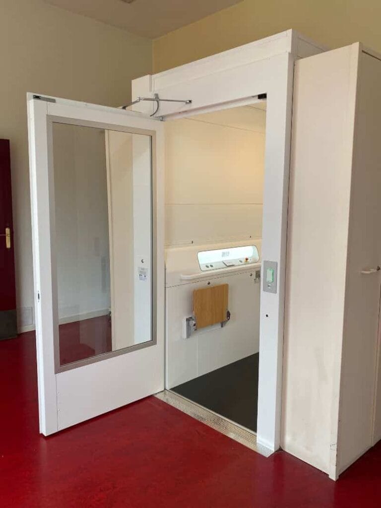 Witte platformlift met openslaande glazen deur in een ruimte met rode vloer in Hilversum