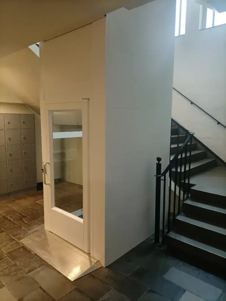 Witte cabinelift naast een klassieke stenen trap in de hal van Sint Jans Den Bosch