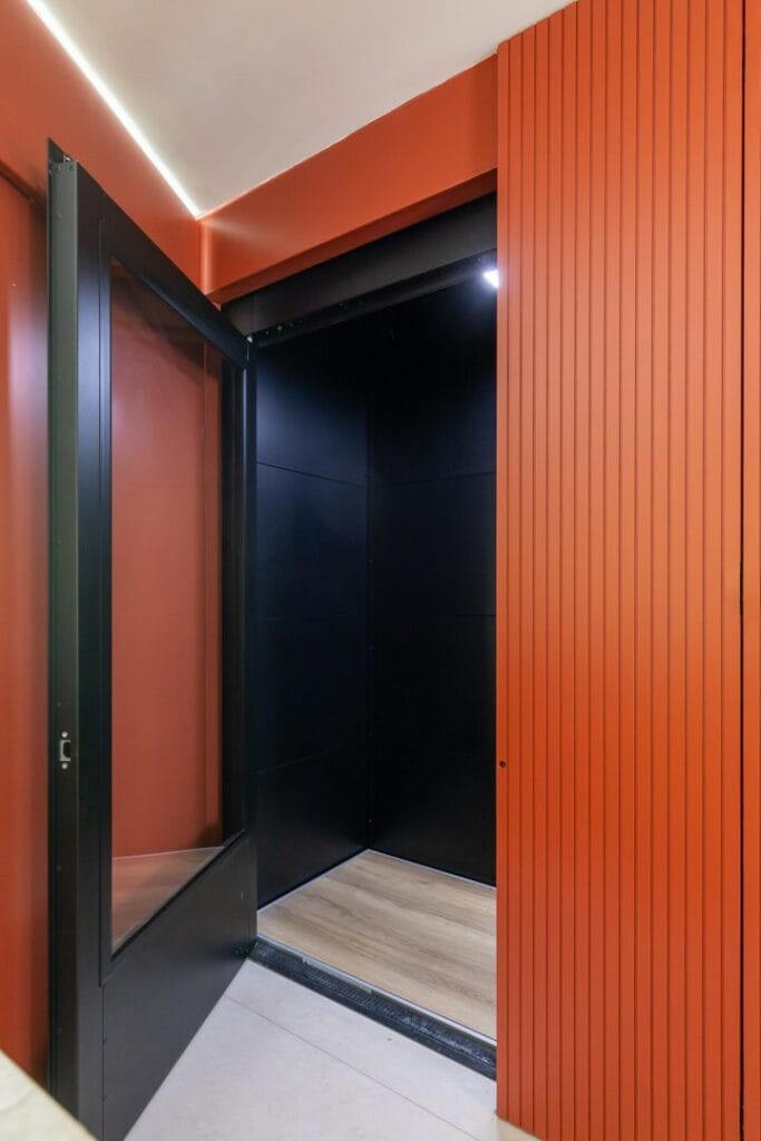 Zwarte cabinelift met open deur en terracotta wandbekleding in een modern woonhuis in Den Haag