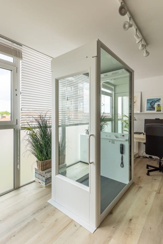 Glazen woonhuislift met open deur geïnstalleerd in lichte woonruimte in Scheveningen