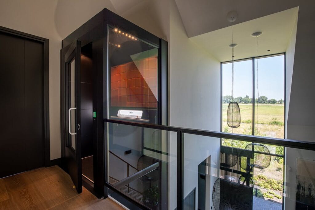 Zwarte woonhuislift met glazen wanden op de overloop van een modern woonhuis in Alphen aan den Rijn