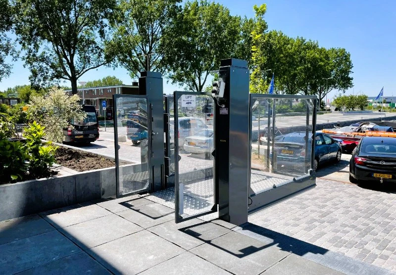 Buitenopgestelde platformlift met glazen wanden op een bestrating bij Havenhuys in Alphen aan den Rijn