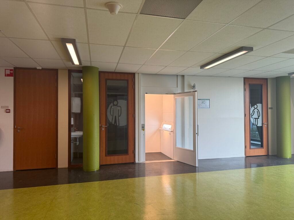 Kleine cabinelift ingebouwd tussen sanitaire ruimten in schoolgebouw Spaarne College Haarlem