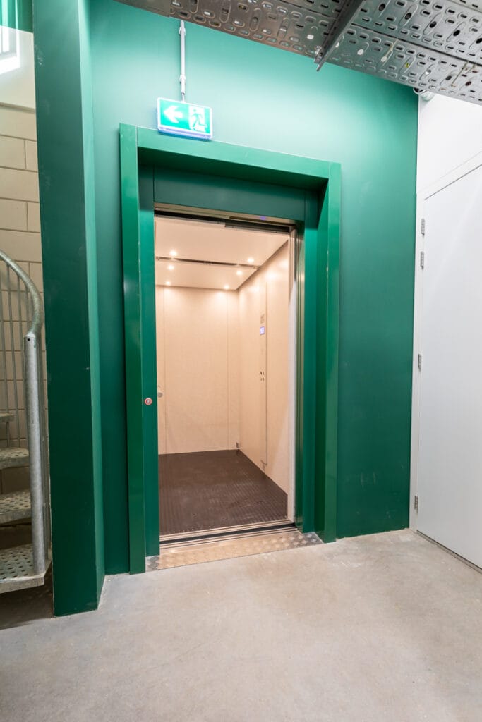 Goederenlift met groene stalen omlijsting in een bedrijfsruimte in Amsterdam
