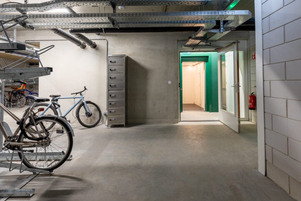 Goederenlift met groene cabine op de begane grond van een fietsenstalling in Amsterdam