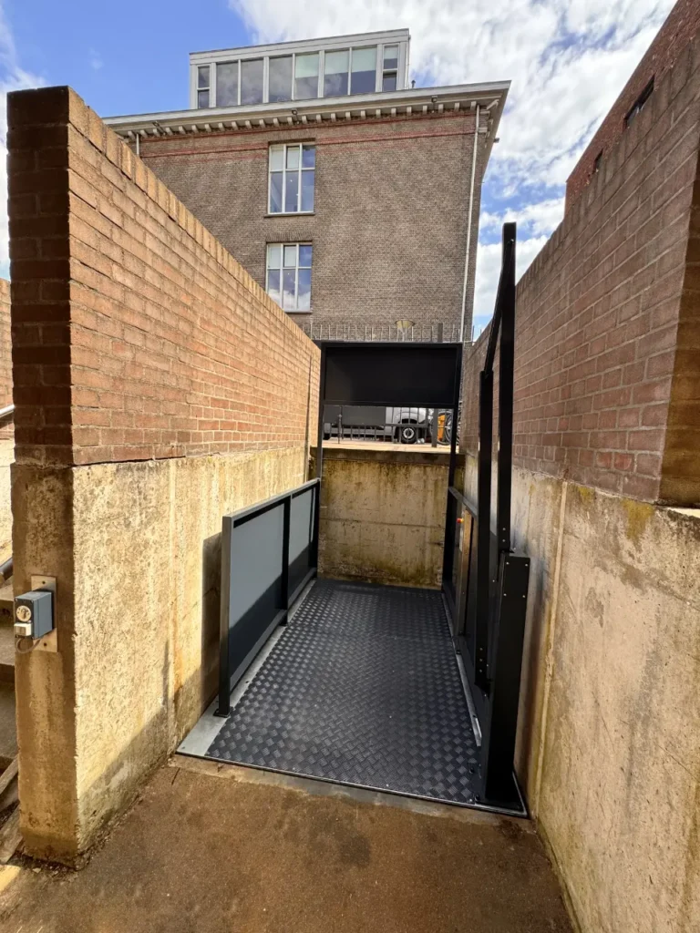 Zwarte platformlift in smalle buitenruimte tussen bakstenen muren in Utrecht