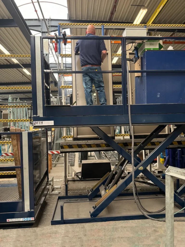 MTH-monteur installeert een industriële heftafel met schaarconstructie in een productiefaciliteit
