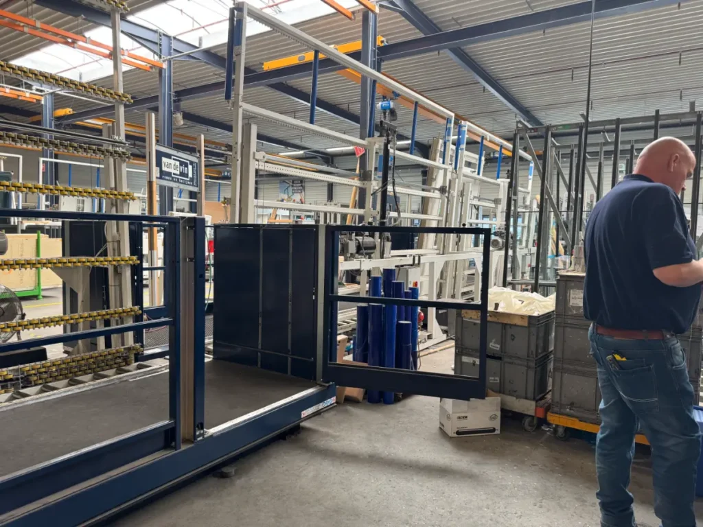 Monteur inspecteert een goederenlift in donkerblauw staal tijdens assemblage in de werkplaats van Van de Vin in Heeze