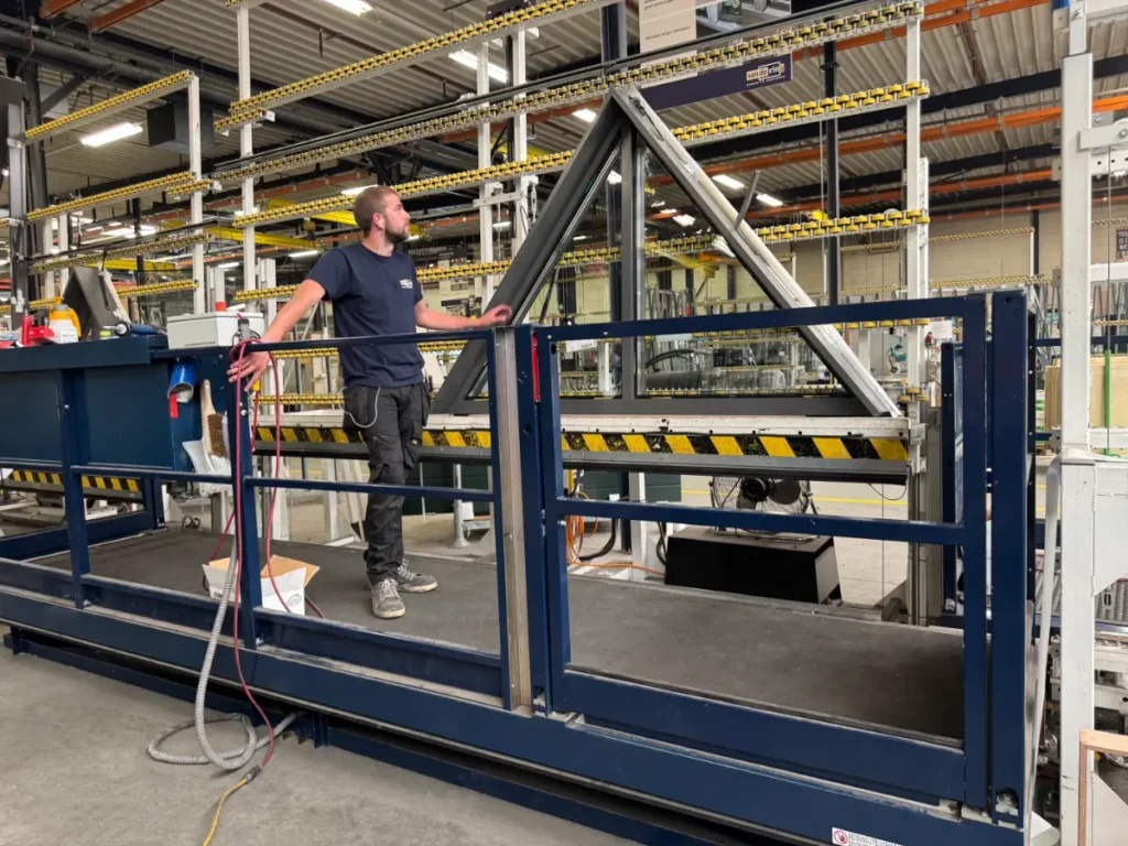Monteur staat op een grote goederenlift tijdens installatie in de productiehal van Van de Vin in Heeze