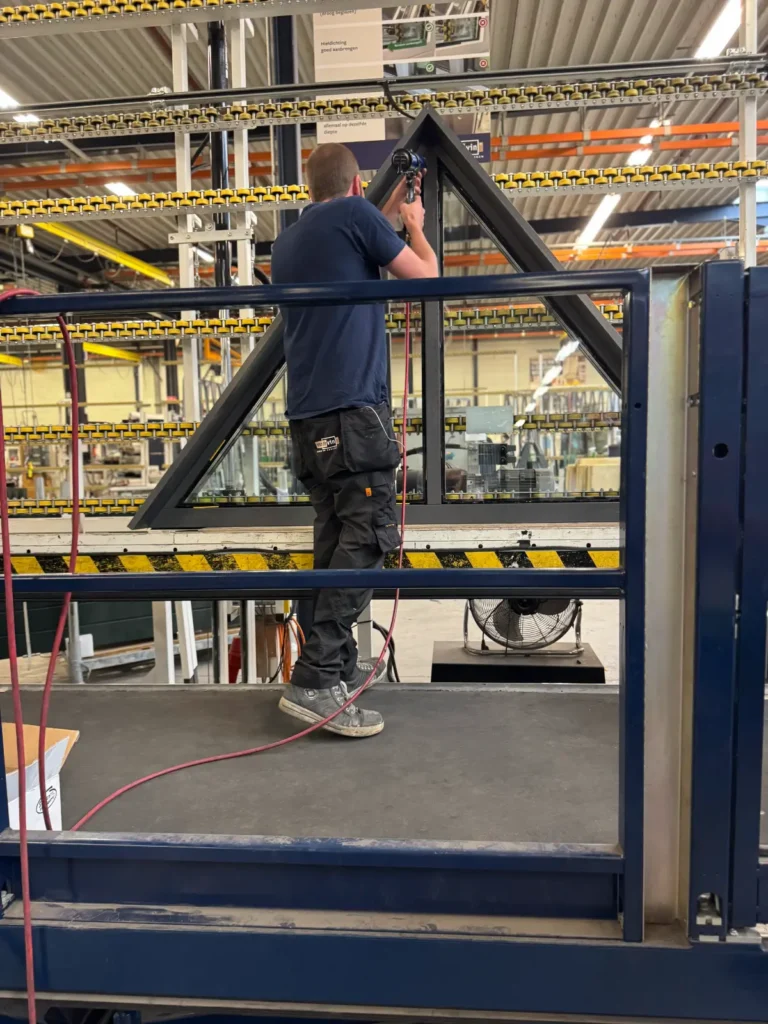 Monteur assembleert een stalen liftschachtframe in een industriële productiefaciliteit