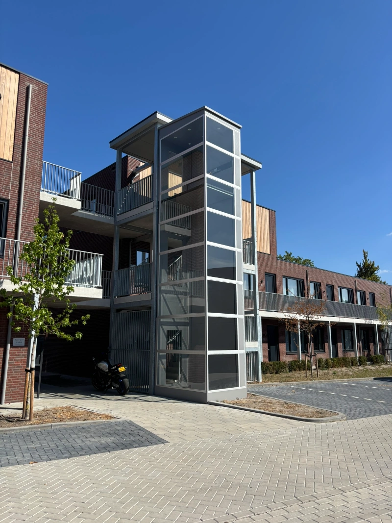 Glazen buitenlift bij moderne appartementen in Waalre met meerdere verdiepingen