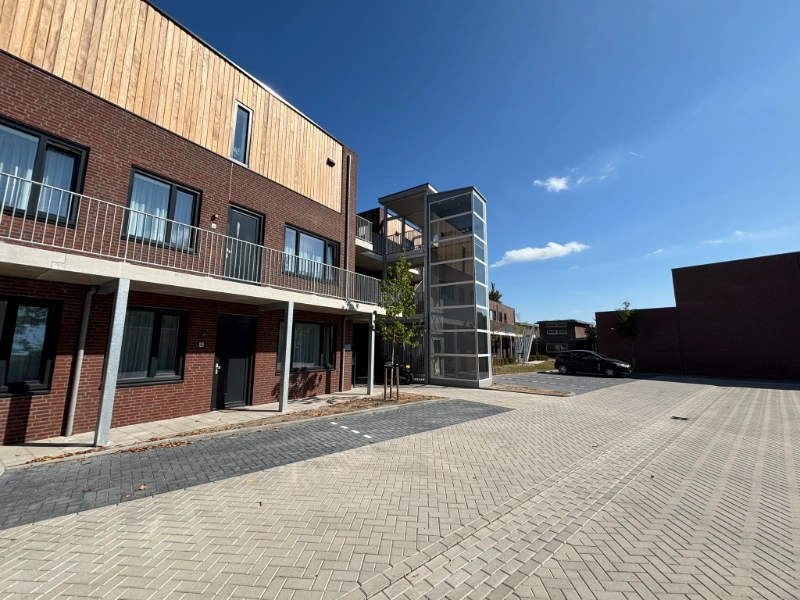 Glazen buitenpersonenlift naast modern appartementencomplex in Waalre
