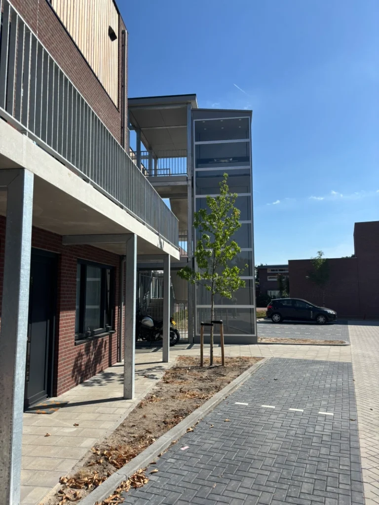 Glazen buitenpersonenlift aan de gevel van een nieuw appartementencomplex in Waalre