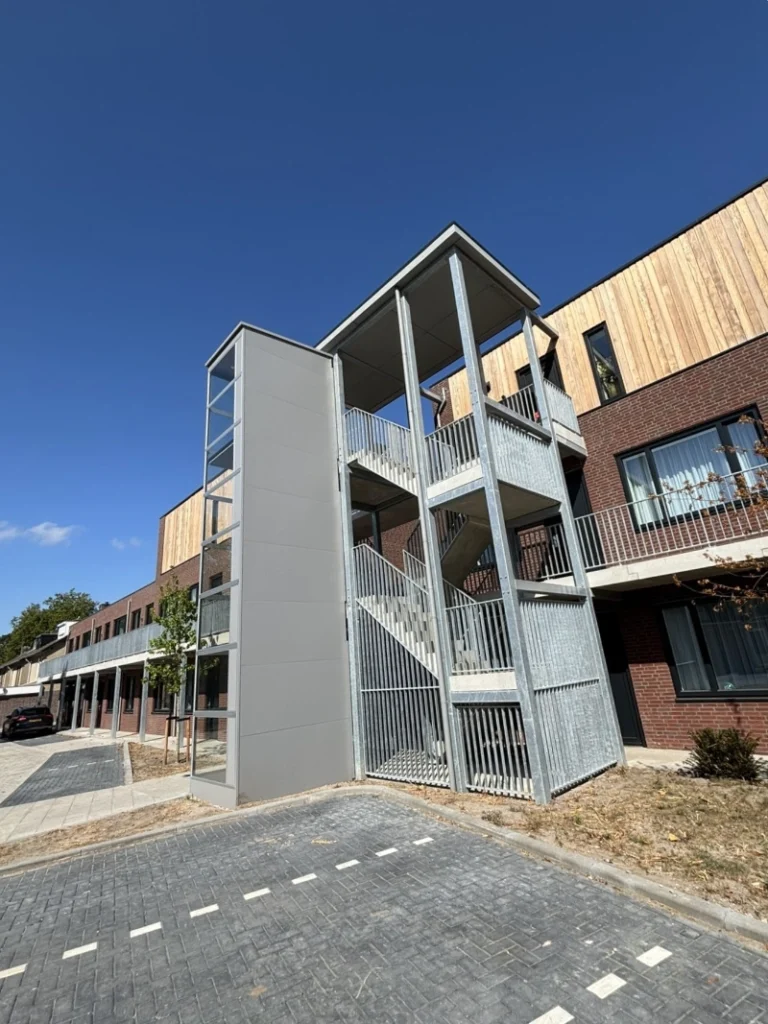 Buitenlift naast een stalen trappentoren bij een appartementencomplex in Waalre