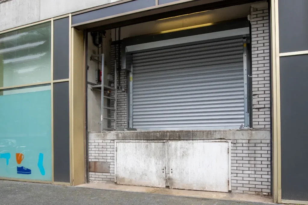 Goederenlift met gesloten rolluik aan de gevel van een supermarkt in Amsterdam