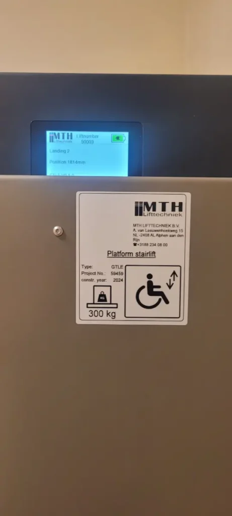 Typeplaatje van een MTH plateautraplift met 300 kg capaciteit geïnstalleerd in een zorginstelling in Breda