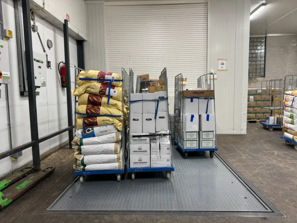 Heftafel in magazijn van Beko in 's-Gravenzande beladen met rolcontainers en goederen