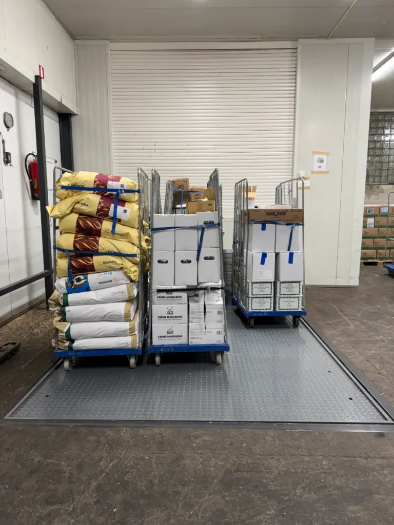Heftafel in magazijn van Beko in 's-Gravenzande beladen met rollcontainers vol goederen