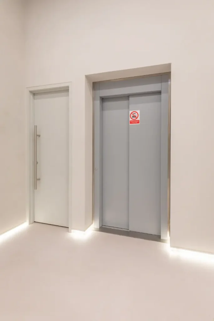 Gesloten liftdeur van een personenlift in de moderne hal van Gymshark Amsterdam