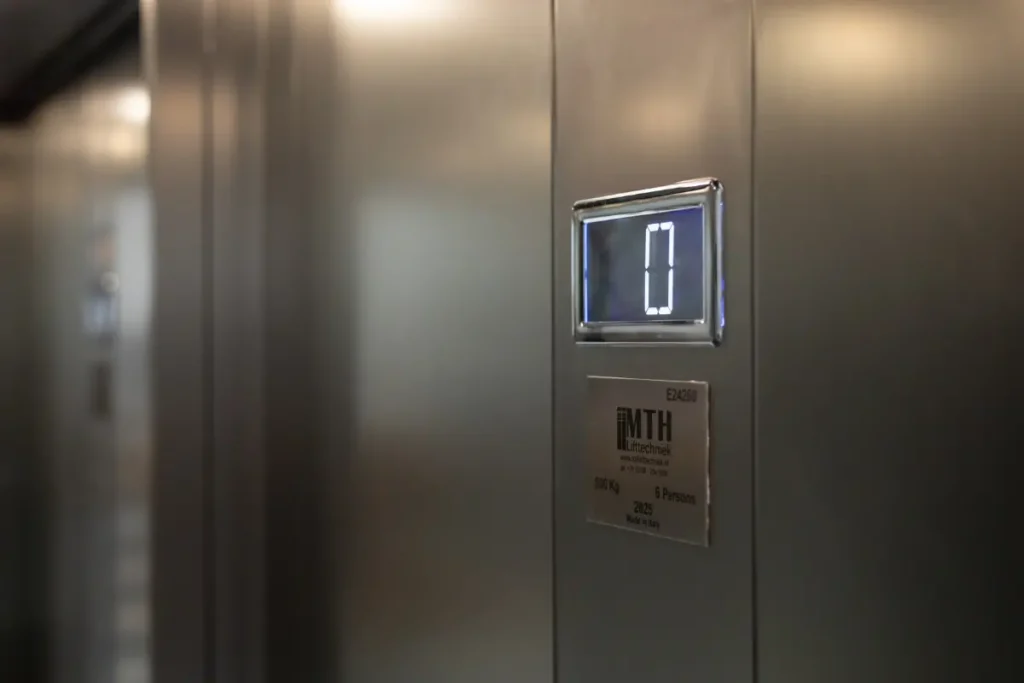 Interieur van een personenlift met verlicht verdiepingsdisplay en MTH Lifttechniek-keuringssticker bij Gymshark Amsterdam