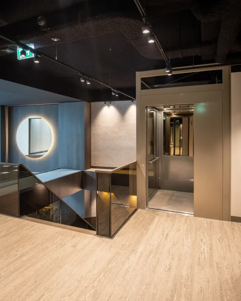 Stijlvolle cabinelift met spiegelwanden naast een designtrap in modern kantoorpand Amstelveen