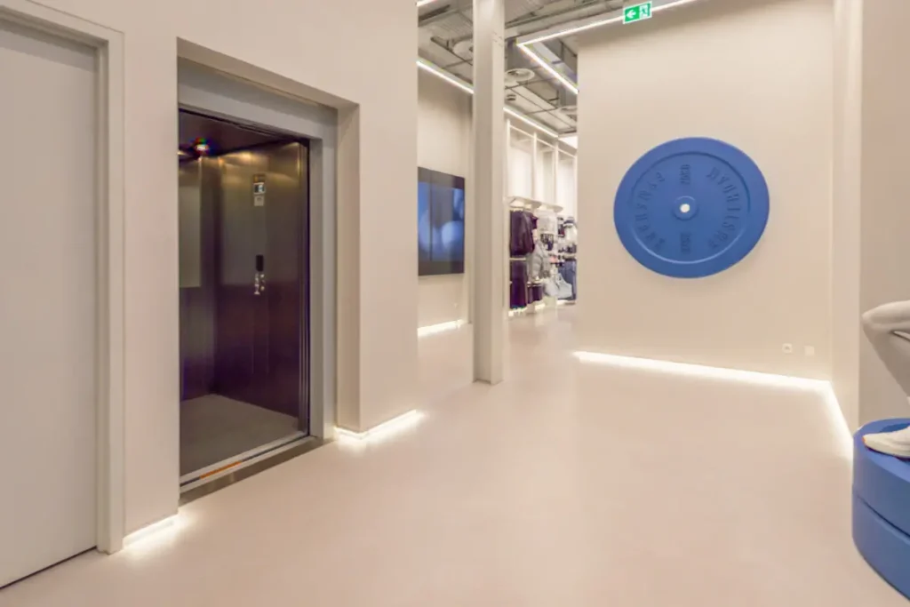Personenlift met donkere spiegeldeuren in de moderne winkel van Gymshark Amsterdam